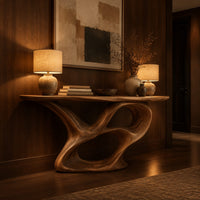 Console table with a winding ribbon base and a long tapered top in an evening entryway with walnut wall paneling