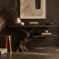 Corner detail of console table with a leaning tree root base and one lower shelf beside wood, brass and linen samples