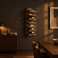 Tall wine rack with stacked angled cradle arms on a slab backboard in a dark dining room at golden hour