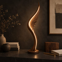 Corner detail of wing shaped wooden floor lamp with a glowing edge line beside wood, brass and linen samples