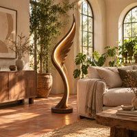 Wing shaped wooden floor lamp with a glowing edge line in a bright living room with arched windows and plants