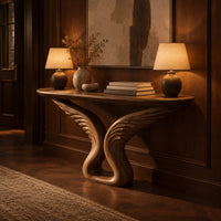 Console table with carved feather wings rising from a looped base in an evening entryway with walnut wall paneling