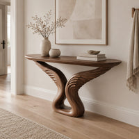 Console table with carved feather wings rising from a looped base in a Scandinavian entryway with white walls