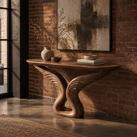 Console table with carved feather wings rising from a looped base in an industrial loft entryway with exposed brick