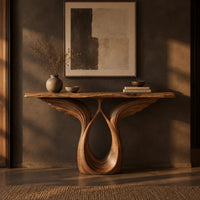 Console table with feather carved wings rising from an open teardrop base in a dark entryway at golden hour
