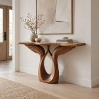 Console table with feather carved wings rising from an open teardrop base in a Scandinavian entryway with white walls