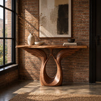 Console table with feather carved wings rising from an open teardrop base in an industrial loft entryway with exposed brick