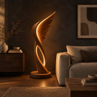 Winged floor lamp with layered feathers and a glowing oval loop in a dark living room at golden hour