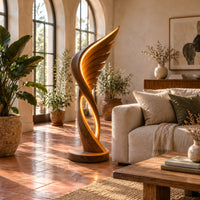 Winged floor lamp with layered feathers and a glowing oval loop in a bright living room with arched windows and plants