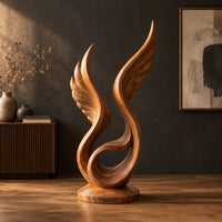 Winged swirl sculpture with carved feather lines on a disc base in a dark studio against a charcoal plaster wall