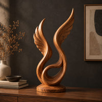 Winged swirl sculpture with carved feather lines on a disc base, three-quarter view showing the grain