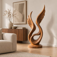 Winged swirl sculpture with carved feather lines on a disc base in a Scandinavian living room with white walls
