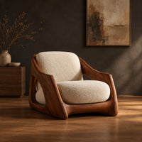 Lounge chair with a carved wooden frame and soft cream cushions in a dark studio against a charcoal plaster wall