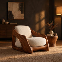 Lounge chair with a carved wooden frame and soft cream cushions in a dark living room at golden hour