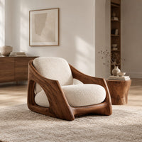 Lounge chair with a carved wooden frame and soft cream cushions in a Scandinavian living room with white walls