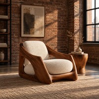 Lounge chair with a carved wooden frame and soft cream cushions in an industrial loft living room with exposed brick