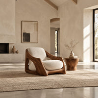 Lounge chair with a carved wooden frame and soft cream cushions in a bright open plan living room