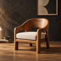 Wraparound lounge chair with arched cutout arms and an upholstered seat in a dark studio against a charcoal plaster wall