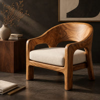 Corner detail of wraparound lounge chair with arched cutout arms and an upholstered seat beside wood, brass and linen samples