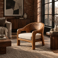 Wraparound lounge chair with arched cutout arms and an upholstered seat in an industrial loft living room with exposed brick