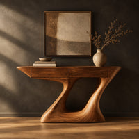 Console table with an angular two panel top on a sculpted z base in a dark studio against a charcoal plaster wall