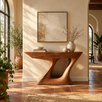 Console table with an angular two panel top on a sculpted z base in a bright entryway with arched windows and plants