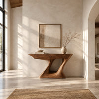 Console table with an angular two panel top on a sculpted z base in a bright open plan entryway