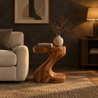 Z shaped side table with a thick top and a flowing sculpted body in a dark living room at golden hour