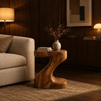 Z shaped side table with a thick top and a flowing sculpted body in an evening living room with walnut wall paneling