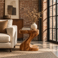 Z shaped side table with a thick top and a flowing sculpted body in an industrial loft living room with exposed brick