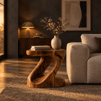 Z shaped side table with a carved diagonal opening and wide base in a dark living room at golden hour