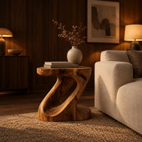 Z shaped side table with a carved diagonal opening and wide base in an evening living room with walnut wall paneling