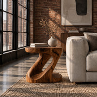 Z shaped side table with a carved diagonal opening and wide base in an industrial loft living room with exposed brick