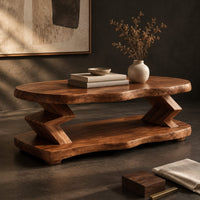 Corner detail of oval coffee table with zigzag supports and a wavy edged lower shelf beside wood, brass and linen samples