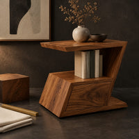 Corner detail of zigzag side table with an angled top, open niche and slanted lower box beside wood, brass and linen samples